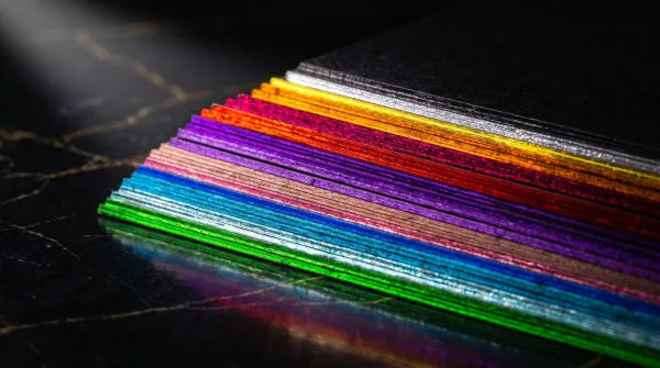 A fanned stack of black cards showing a rainbow of painted color edges.