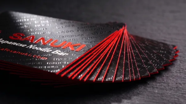 A thick black card with red-painted edges, fanned to show its weight.