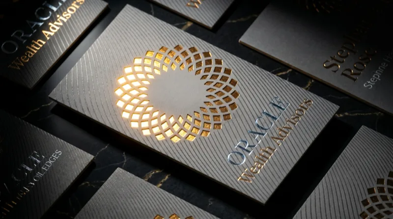 A multi-board business card with a gold laser face cut catching the light through the card's middle board