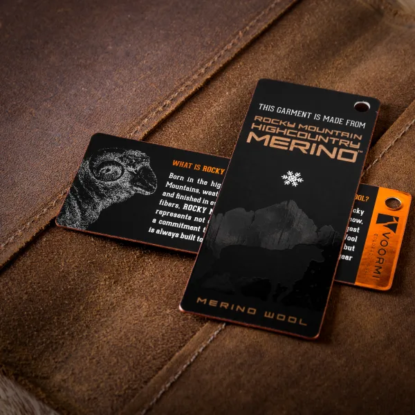 A black soft-touch hang tag reading Merino Wool, with copper foil text and a sheep illustration.