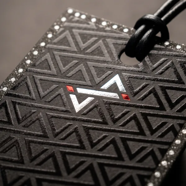 A black hang tag with an embossed triangular pattern and a small metallic logo mark.