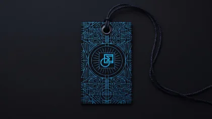 A black hang tag with a glowing teal geometric foil pattern and logo, hanging from a black cord against a matching black background.