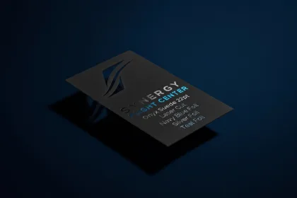 An onyx black suede card for Synergy Flight Center with navy blue, silver and teal foil detailing.