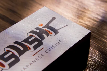 A stack of uncoated business cards for a Japanese cuisine restaurant with copper foil and clear embossed line work.