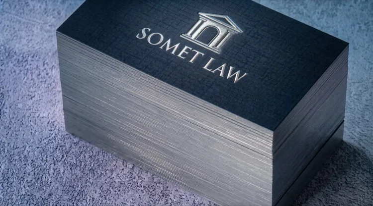 Somet Law business card with a silver foil emblem embossed on dark navy woven linen stock