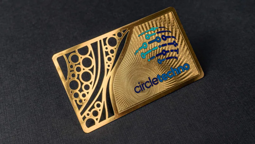 A gold metal business card laser-cut with a geometric pattern and an intricate "circletechno" tech-company logo.